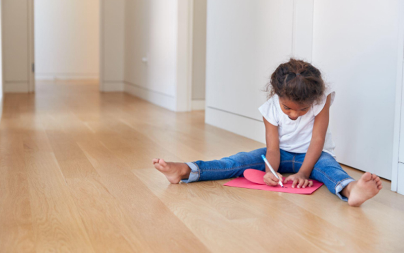 A Little Girl Sitting on the Floor Making a Card for Mother's Day.