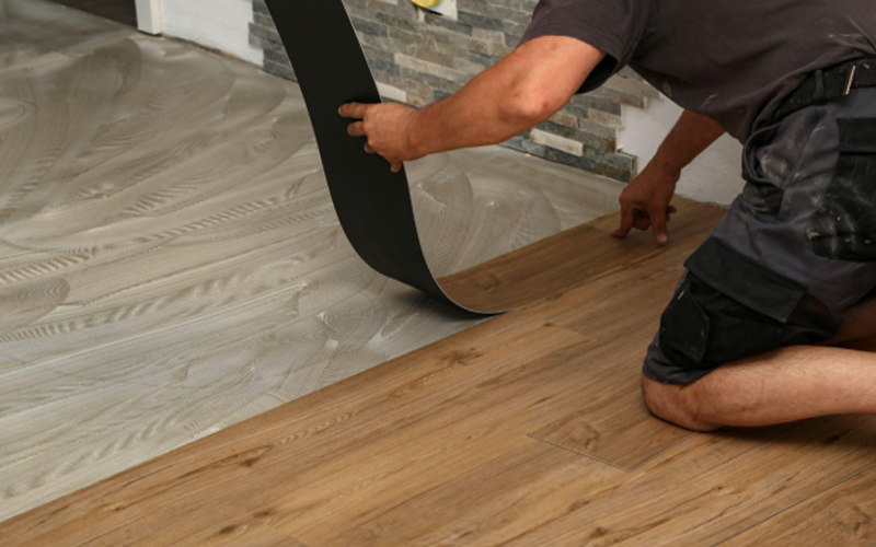 Worker installing new parquet vinyl tiles on the floor