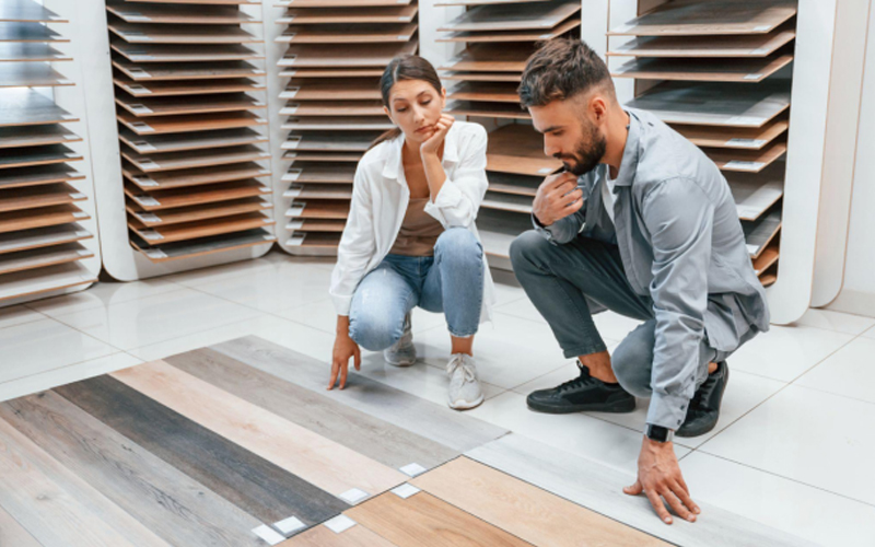Couple examining wood-look flooring samples in showroom.