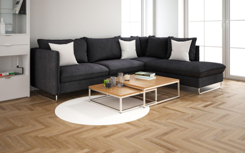 Modern interior design of living room with a black sofa, nested coffee tables, and a herringbone wood texture.