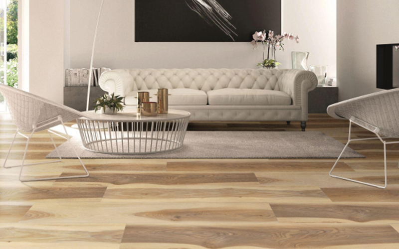 Stylish interior design featuring a white sofa, metal chairs, and natural light, wood look vinyl plank flooring.