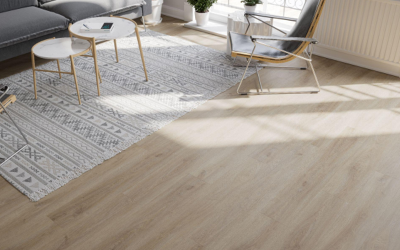 A modern living room with light wood look vinyl flooring and patterned rug.