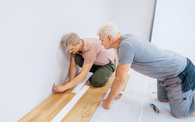 Father and adult son installing flooring in new Home by their own.
