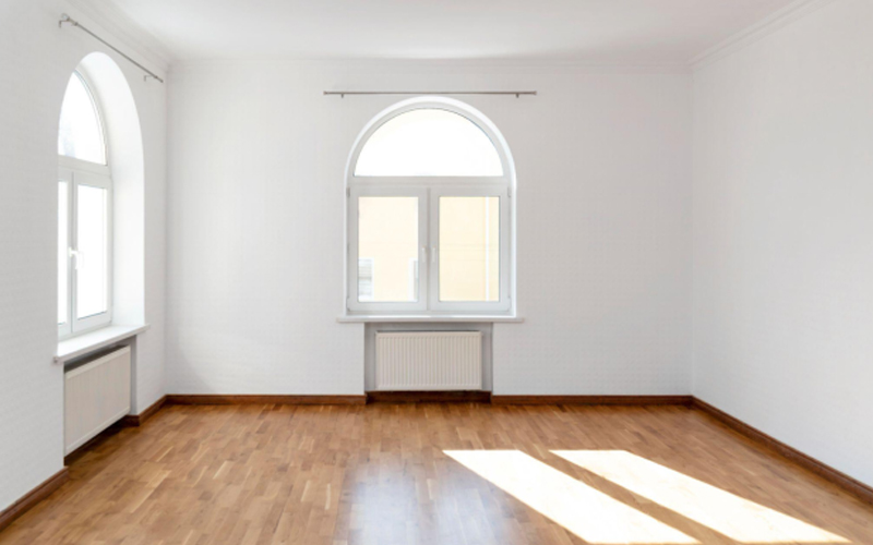 Empty white room with arched windows and flooring.