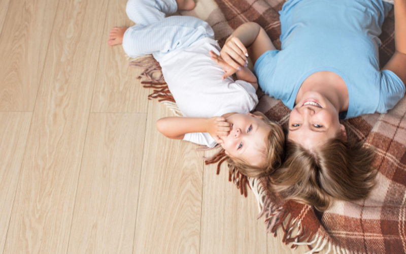  A boy and his mother lying on wood-look SPC flooring, enjoying a moment of relaxation together.