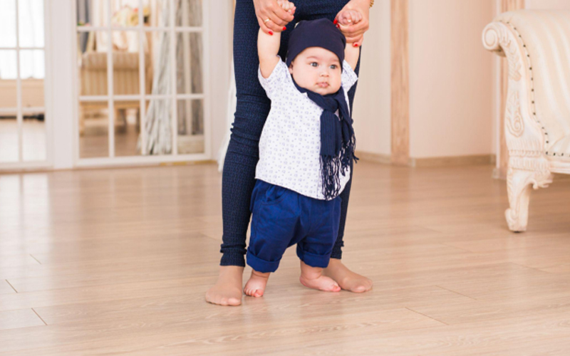 Mom teaching her son to take first steps on light wood LVT flooring