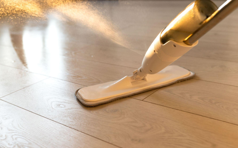 A person is mopping the floor with a spray mop.