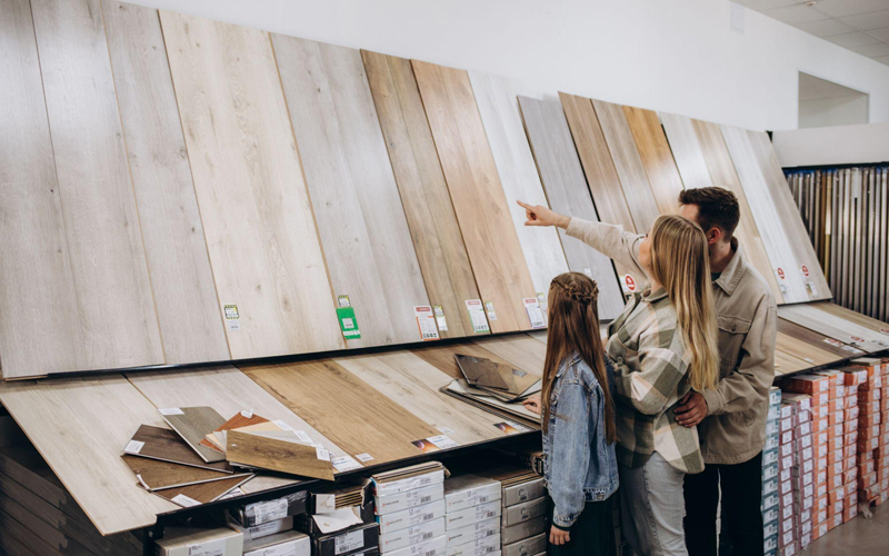 Modern family couple standing together with sample of SPC flooring in a building store.