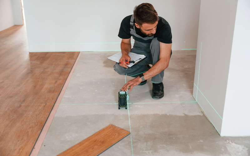 The worker is installing LVT flooring in a herringbone pattern