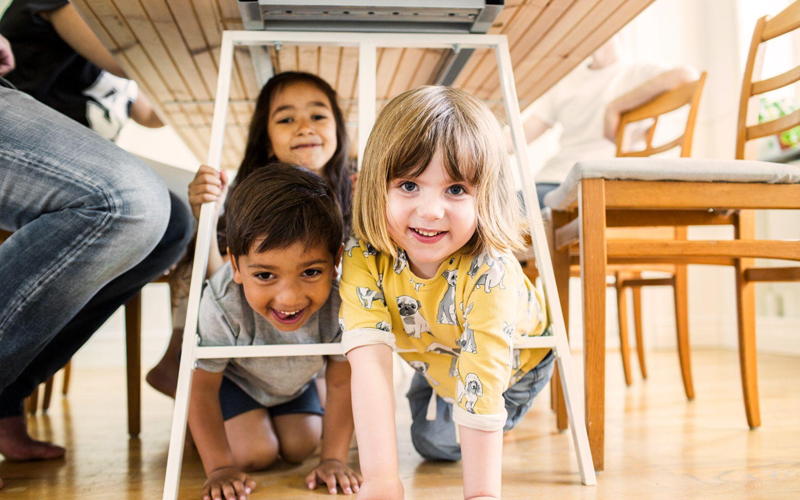 A group of children playing under a table.