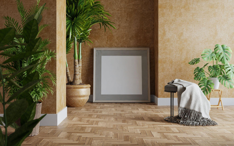 Modern room with gray frame on beige wall, tropical plants, and herringbone vinyl flooring.